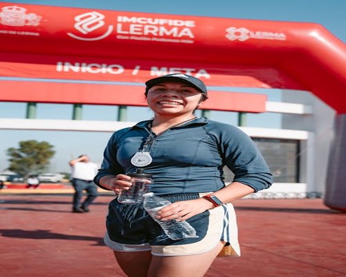Persona hidratándose con una botella de agua mientras camina